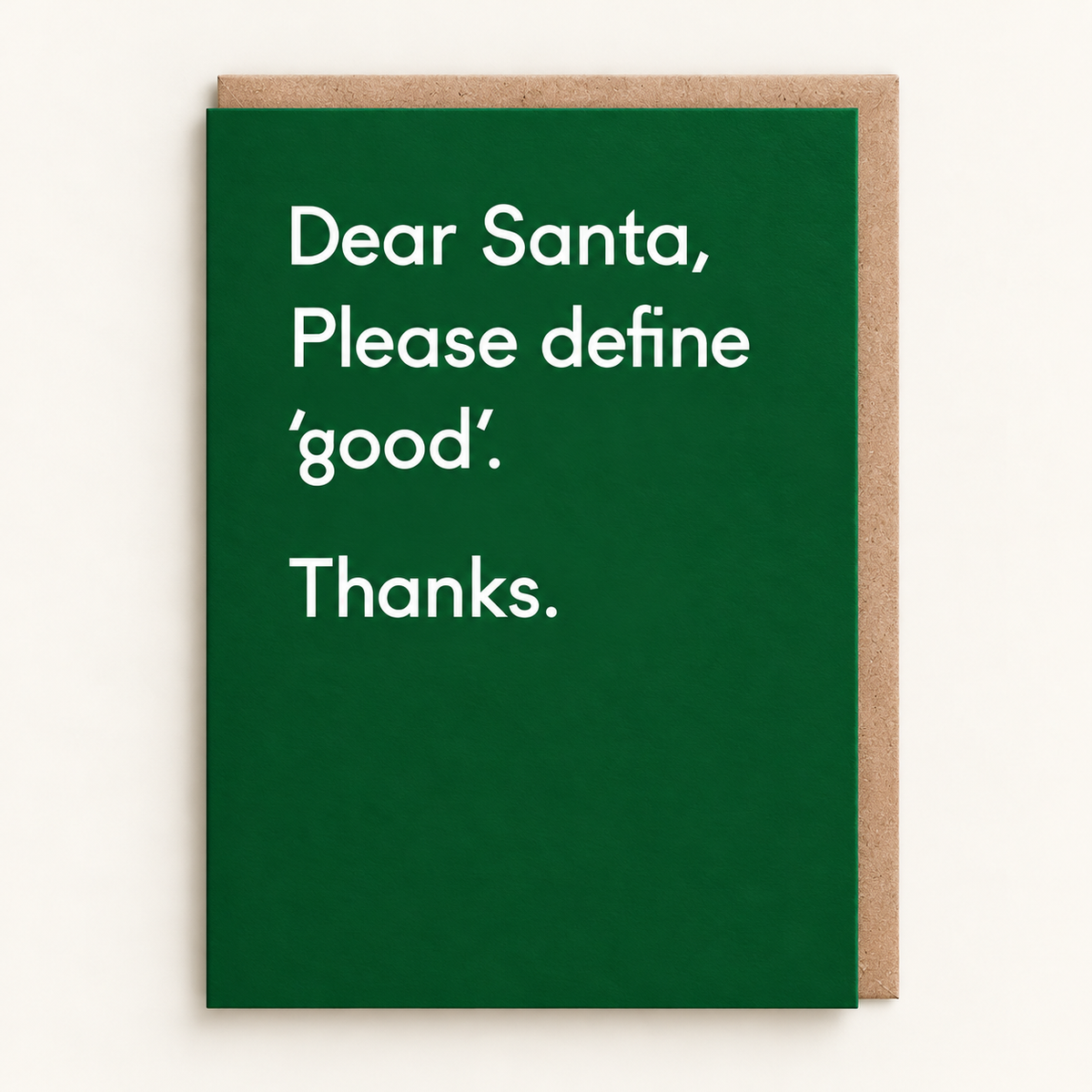 Please Define Good Christmas Card by Twin Pines: white type reading Dear Santa, please define good. Thanks. on a deep green card, with a brown kraft envelope behind