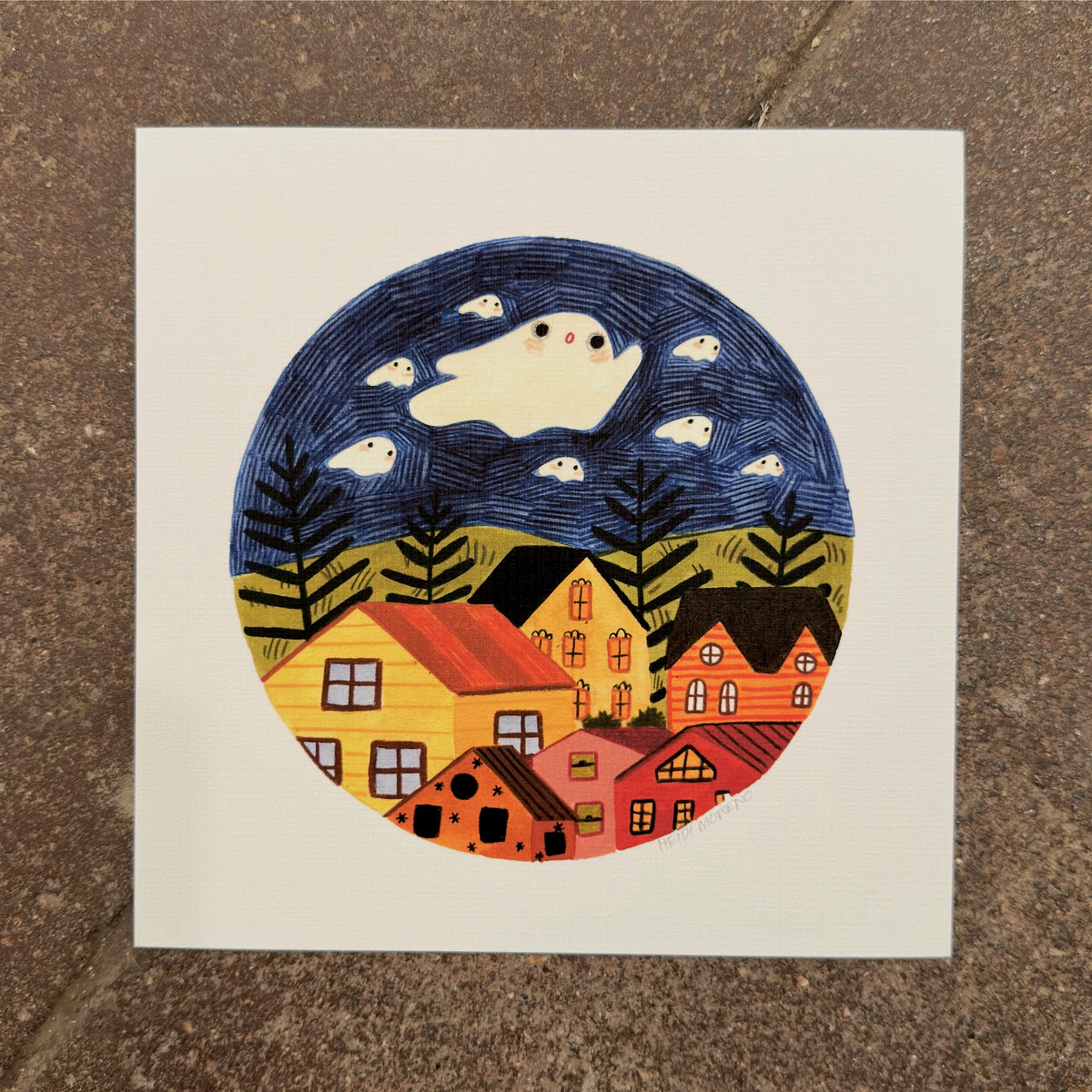 Large white ghost and small ghosts floating in a navy sky above ferns, green hills and colorful houses inside a circle, art print by Heidi Moreno on display at We Are 1976