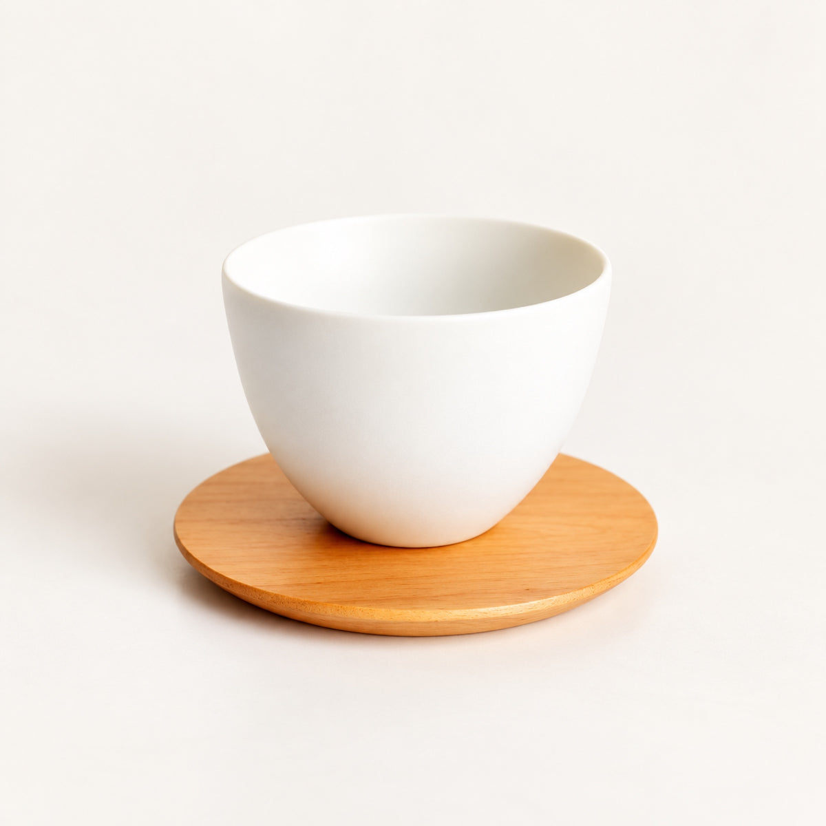 Round SALIU cherry wood coaster holding a white ceramic teacup