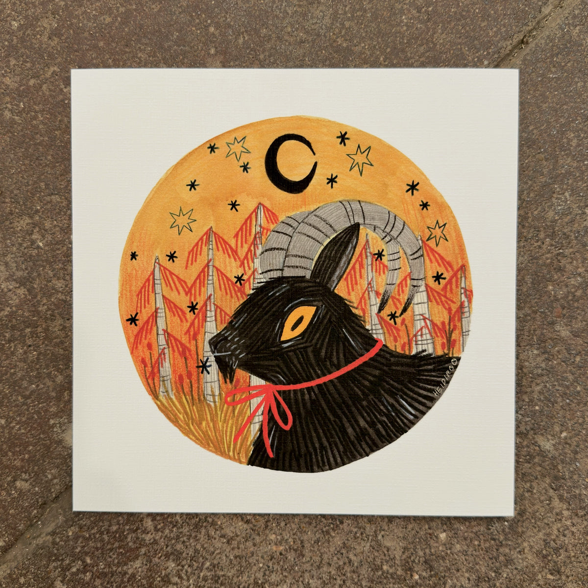 Black goat with curling gray horns and an orange eye wearing a red ribbon, in an orange circle with red pines, stars and a crescent moon, art print by Heidi Moreno on display at We Are 1976
