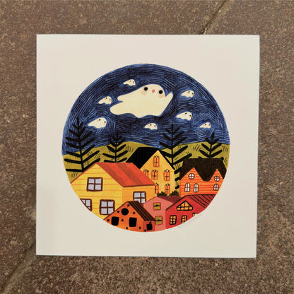 Large white ghost and small ghosts floating in a navy sky above ferns, green hills and colorful houses inside a circle, art print by Heidi Moreno on display at We Are 1976