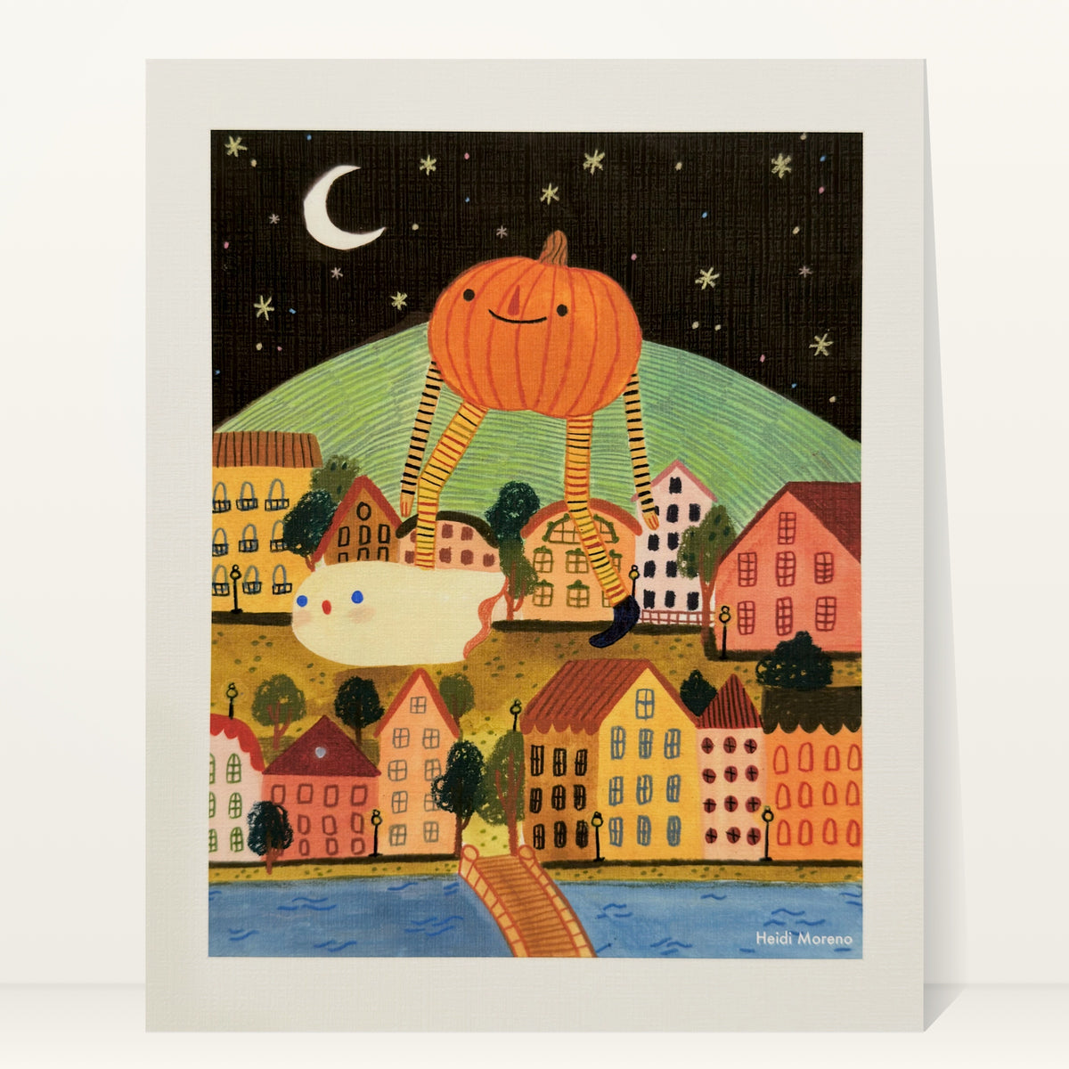 Giant smiling pumpkin on long striped legs walking over a colorful hillside town at night with a small ghost and a crescent moon, art print by Heidi Moreno