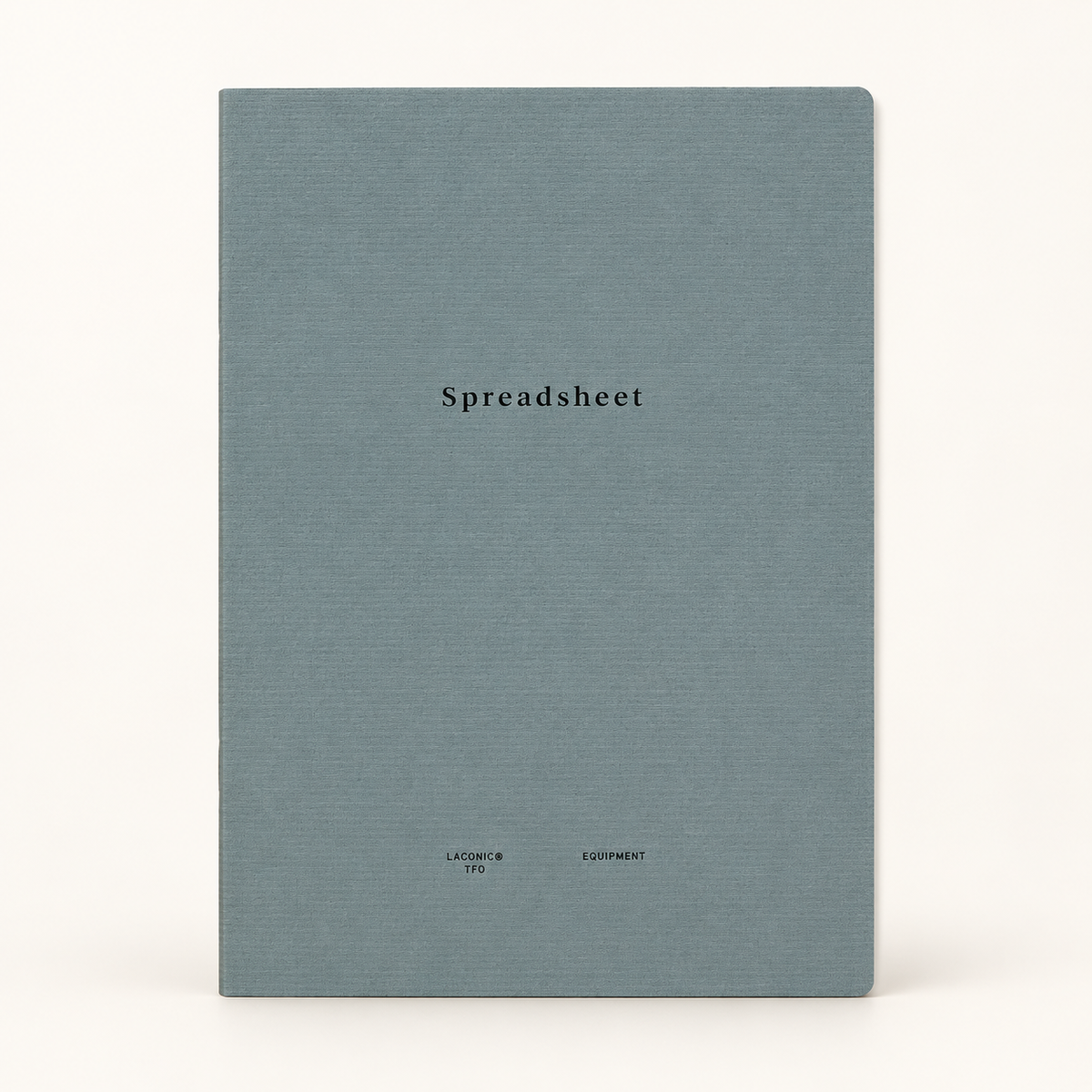 A square notebook with a textured slate blue cover and the word 'Spreadsheet' printed in black serif font in the center, set against a plain off-white background.