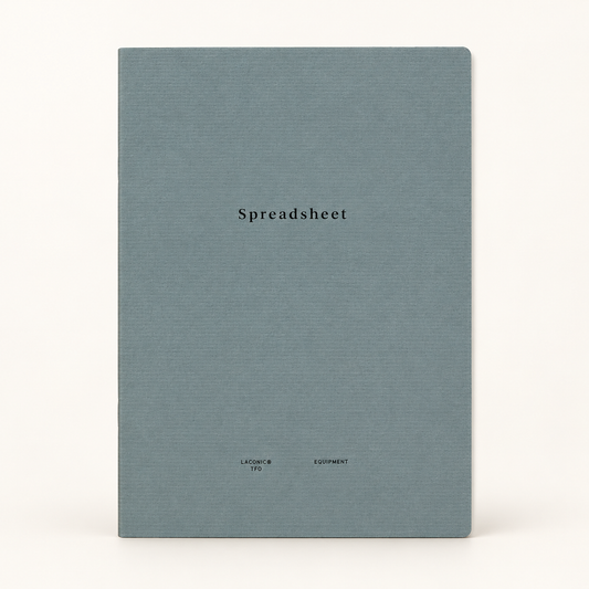A square notebook with a textured slate blue cover and the word 'Spreadsheet' printed in black serif font in the center, set against a plain off-white background.
