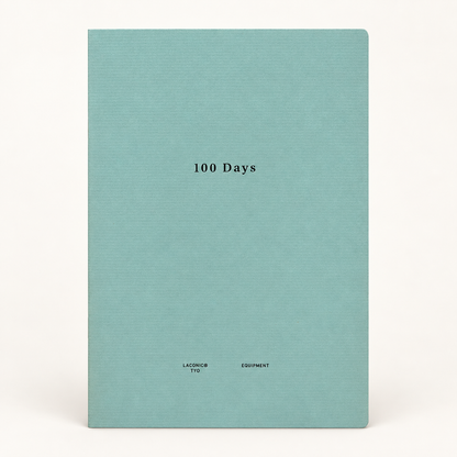 A hardcover notebook or journal with a textured light teal cover, featuring the title '100 Days' printed in black serif font in the center, and 'LACONIC EQUIPMENT' printed at the bottom. The notebook is photographed against a clean, off-white background.