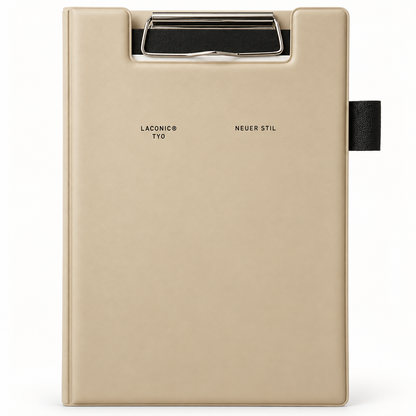 A beige clipboard-style notebook cover with a black clip area, small black text reading 'LACONIC TYO' and 'NEVER STILL', and a black side tab, shown on a white background.