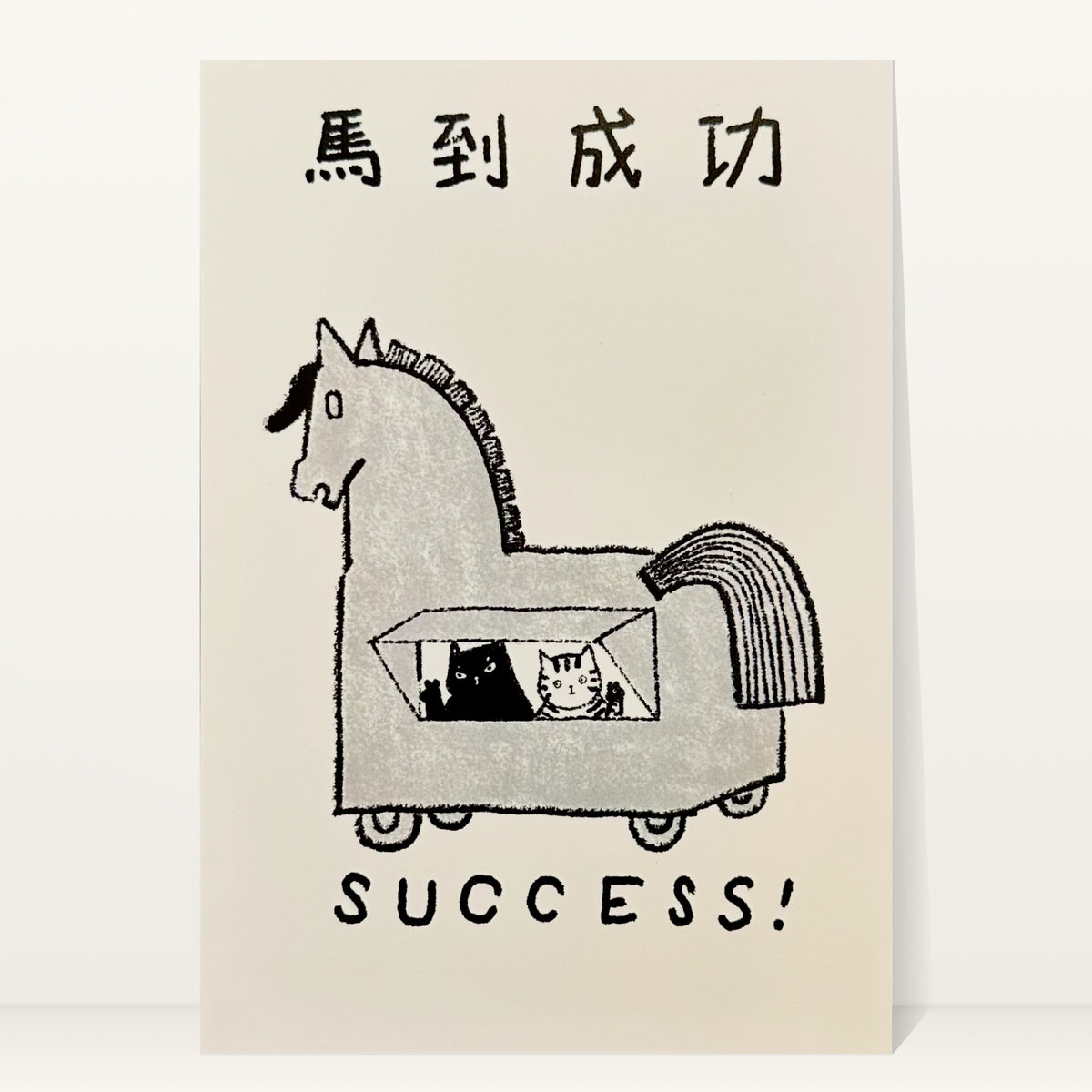 Success mini art print by Linnan Ye: two cats peeking out of a wooden horse on wheels, with the Chinese idiom 馬到成功 and the word “Success!”