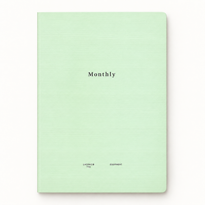 A mint green hardcover notebook with a subtle horizontal ribbed texture, featuring the word 'Monthly' printed in black serif font in the center and small text at the bottom.