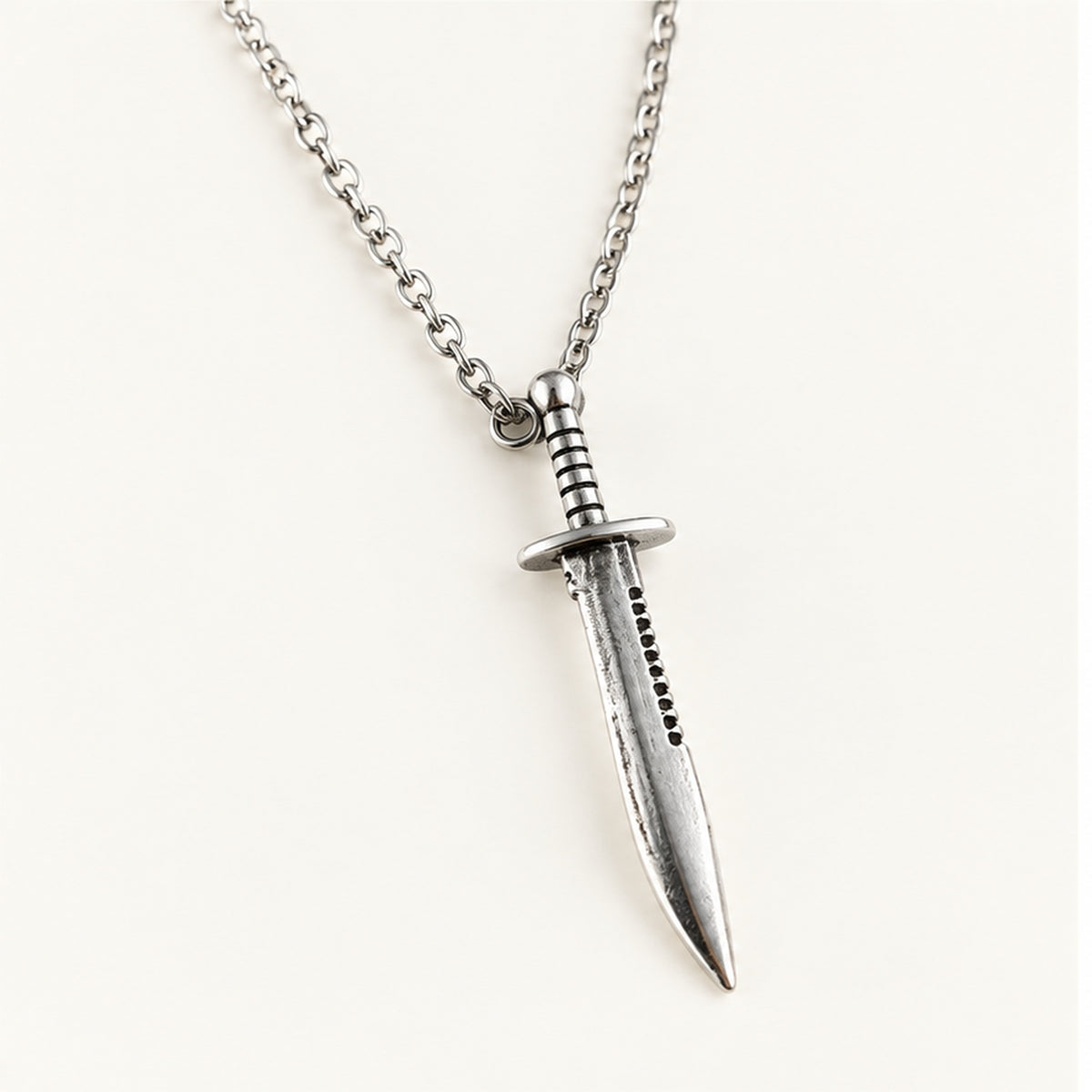 Close-up of the silver Bowie knife pendant showing crossguard, grip, and serrated spine