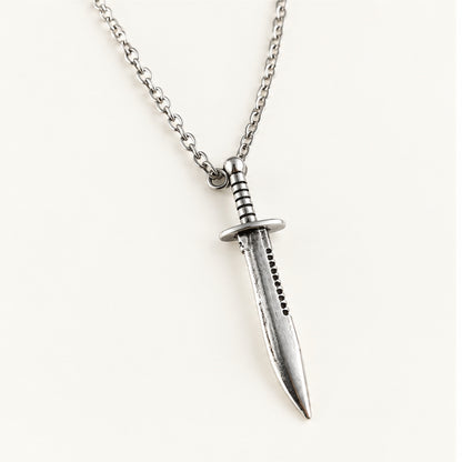 Close-up of the silver Bowie knife pendant showing crossguard, grip, and serrated spine