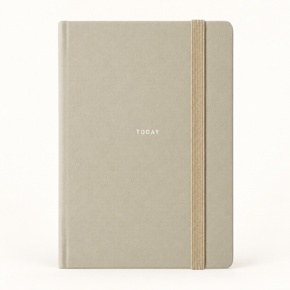 A minimalist hardcover notebook with a textured light gray-beige cover, featuring the word 'TODAY' printed in small white letters and a vertical elastic closure band in a natural tan color, set against a plain white background.