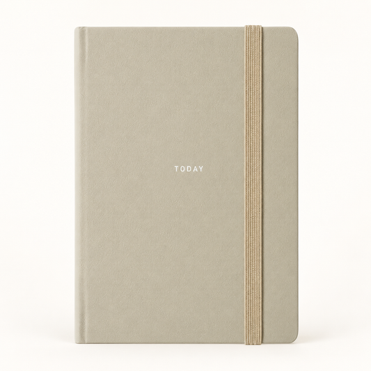 A minimalist hardcover notebook with a textured light gray-beige cover, featuring the word 'TODAY' printed in small white letters and a vertical elastic closure band in a natural tan color, set against a plain white background.