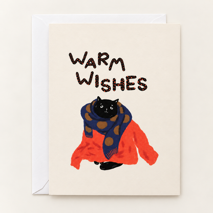Warm Wishes greeting card by Linnan Ye with white envelope: black cat bundled in a red sweater and navy polka-dot scarf beneath hand-lettered “Warm Wishes”