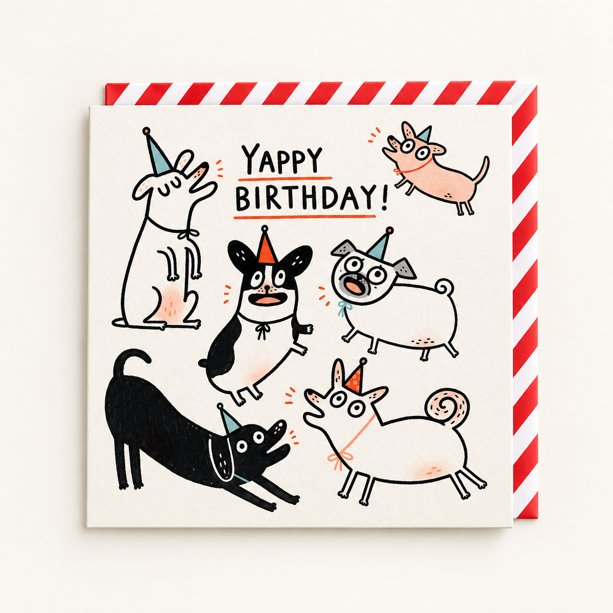 Yappy Birthday Greeting Card by Gemma Correll: six line-drawn dogs in party hats barking around the words Yappy Birthday on a cream square card, with a red and white striped envelope